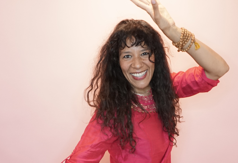 Charisma Whitefeather, Kundalini Yoga teacher in Los Angeles, wearing a bright pink kurti, dancing and smiling